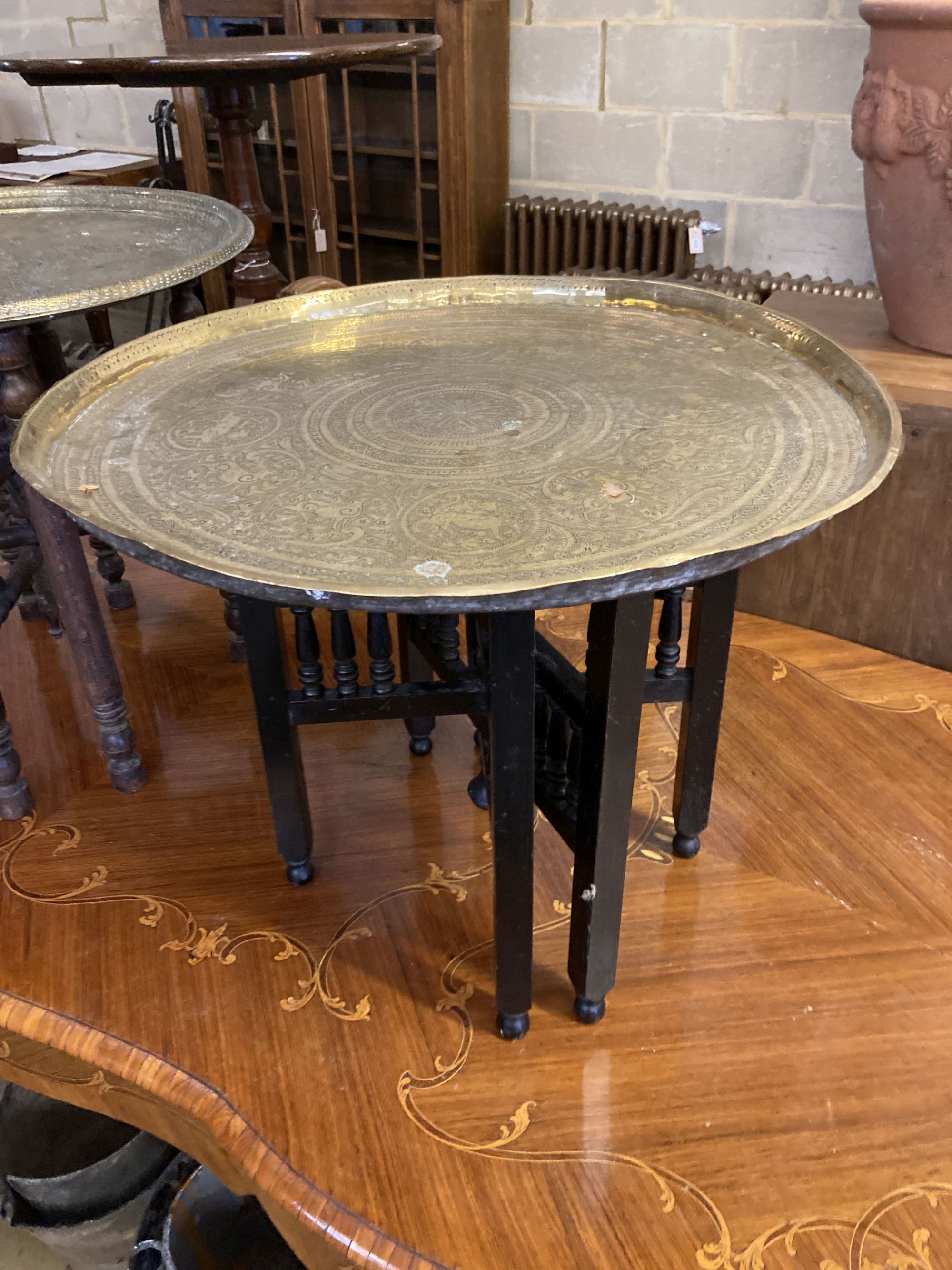 Two Benares engraved circular tray top tables, larger 59cm diameter, 53cm high